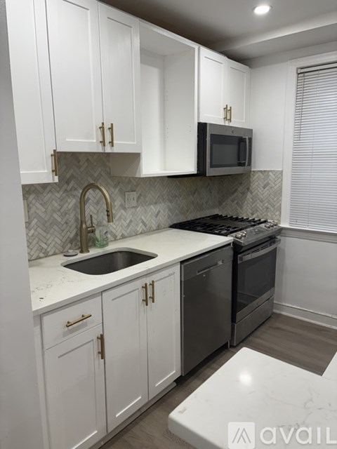 A kitchen with white cabinets and a black microwave above the stove.