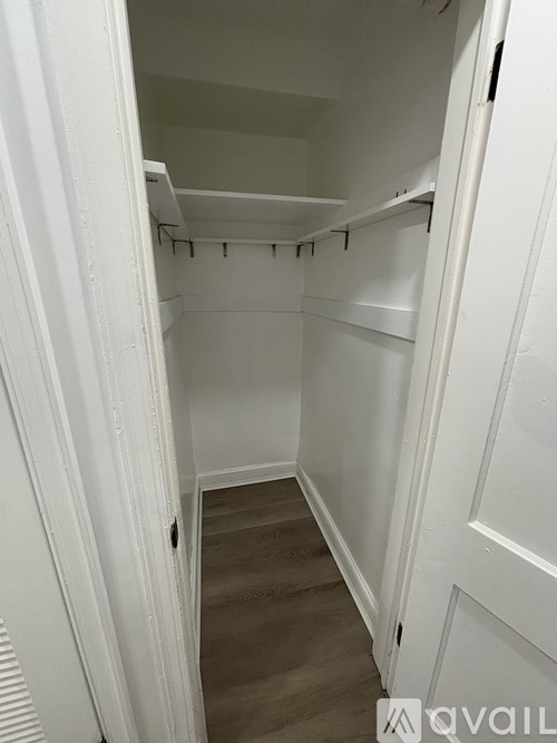 A white closet with a wooden floor and white walls.