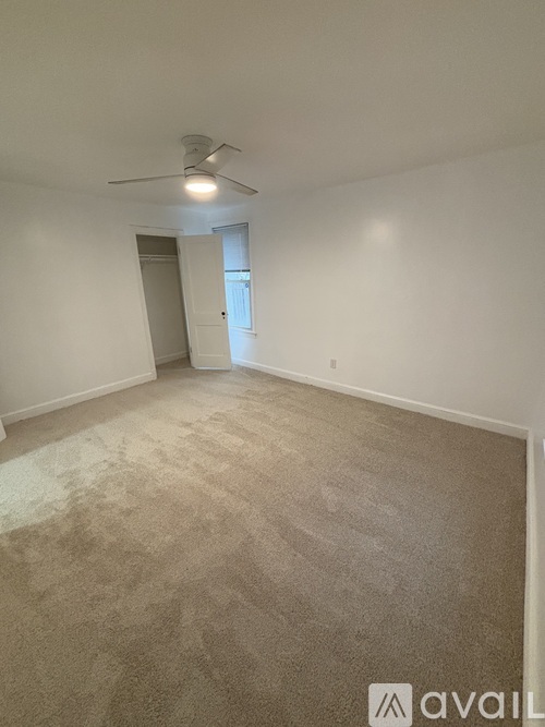 A room with a carpeted floor and a ceiling fan.