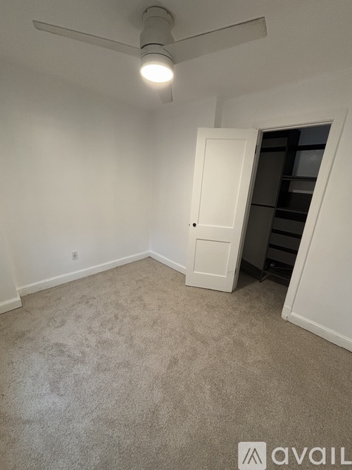 A room with a ceiling fan and a door leading to a hallway.