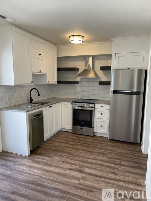 A kitchen with white cabinets and a wooden floor.