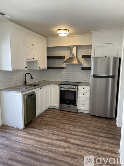 A kitchen with white cabinets and a wooden floor.