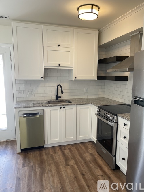 A kitchen with white cabinets and a black countertop.