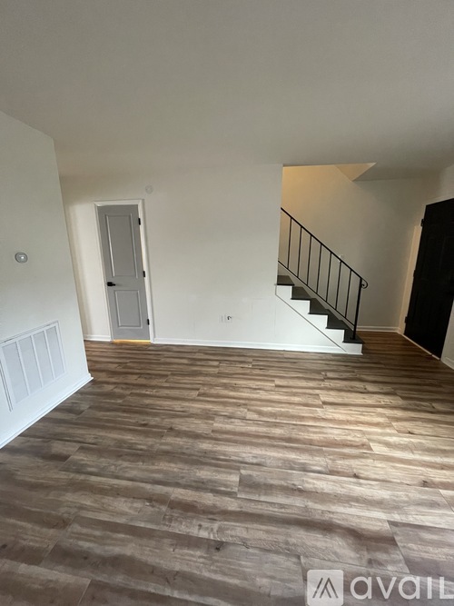 A room with wooden flooring and a staircase with a metal railing.