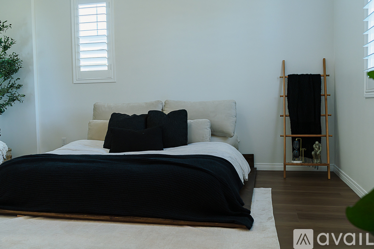 A bedroom with a white bed and a black blanket.