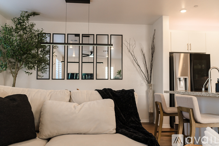 A modern living room with a white couch and a black throw blanket.