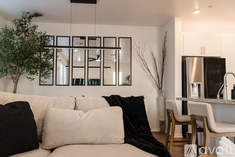 A modern living room with a white couch and a black throw blanket.