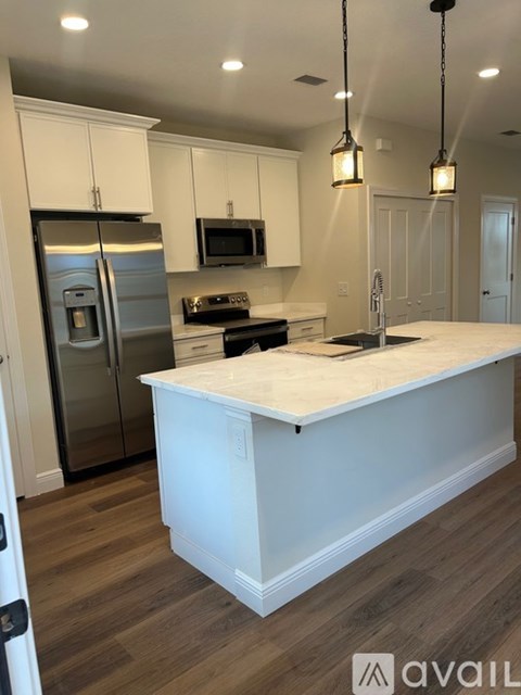 A kitchen with a white island and stainless steel appliances.