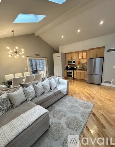 A modern living room with a grey sofa and a kitchen in the background.