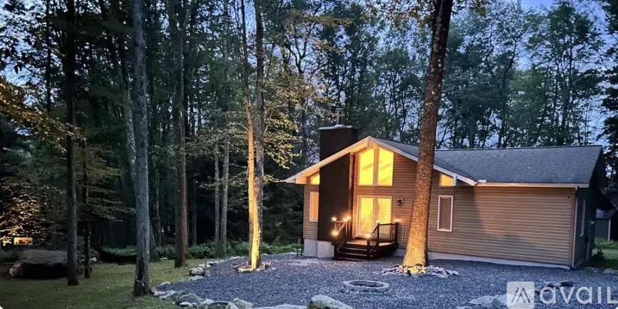 A house with a brown roof and a porch is surrounded by trees.