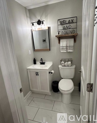 A bathroom with a toilet, sink, and mirror.