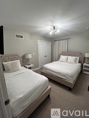Two beds in a bedroom with white bedding and carpet.