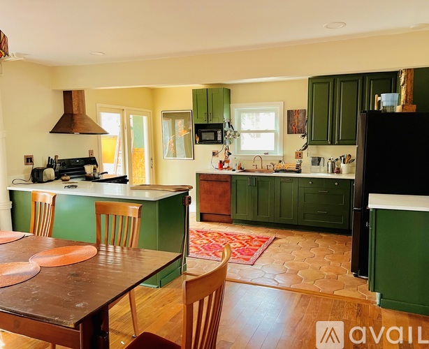 A kitchen with green cabinets and a wooden table.
