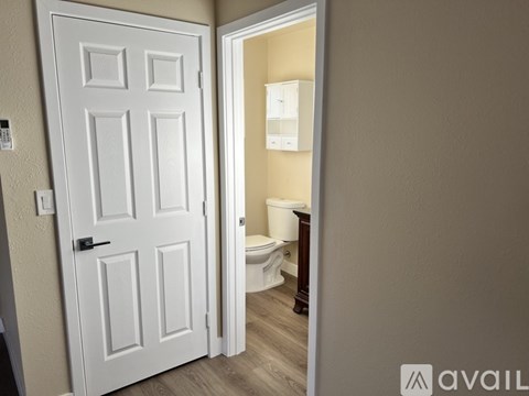 A white door is open to a bathroom with a toilet and a cabinet.