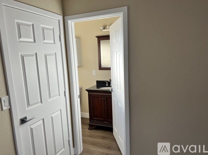 A white door is open to a room with a brown cabinet and a mirror.