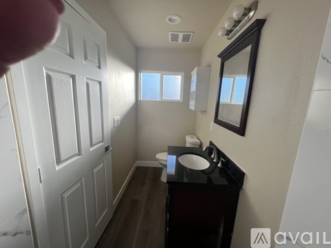 A bathroom with a toilet, sink, and mirror.