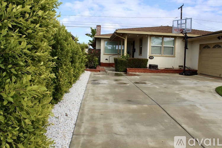 A house with a driveway and a hedge on the left.