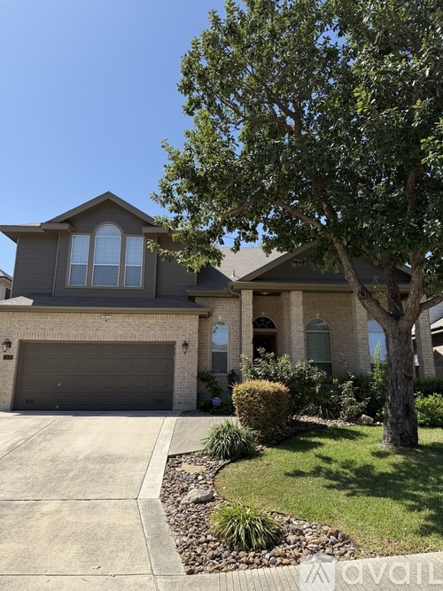 A house with a grey garage door and a tree in front.