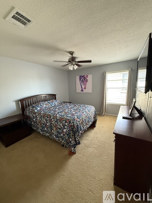 A bedroom with a bed, dresser, and television.