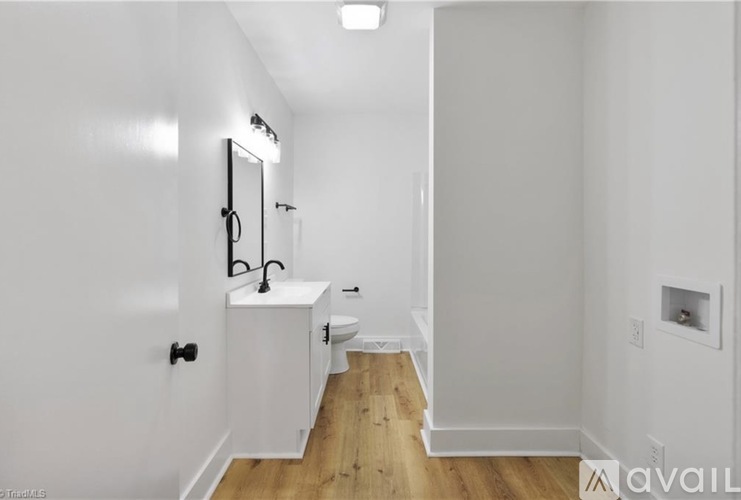 A white bathroom with a wooden floor and a white cabinet.