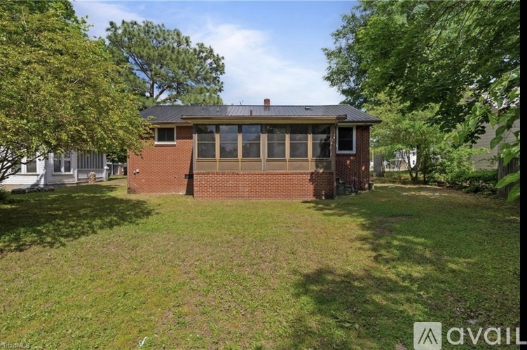 A house with a brick exterior and a large lawn in front.