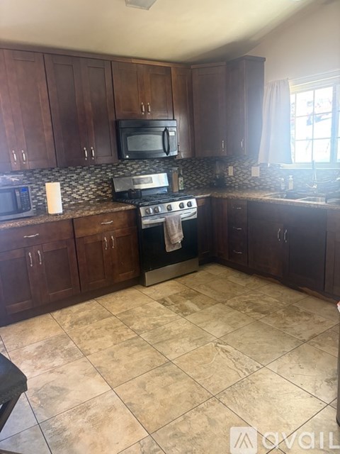 A kitchen with brown cabinets and a black stove top oven.