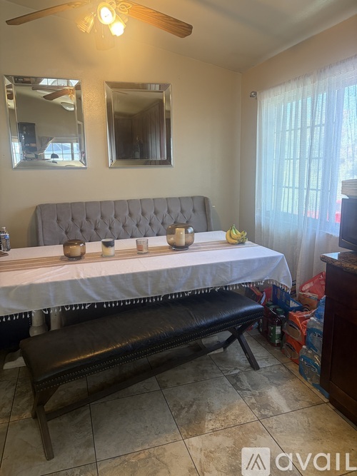 A dining room with a table set for two and a bench.