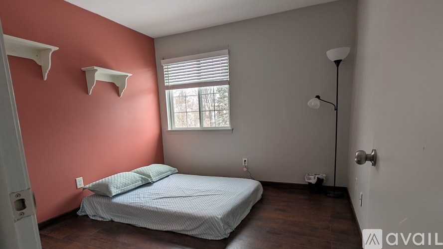 A bedroom with a bed, pillows, and a lamp.