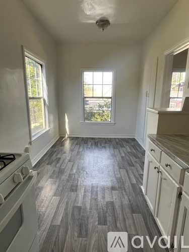 A kitchen with a stove, cabinets, and a window.