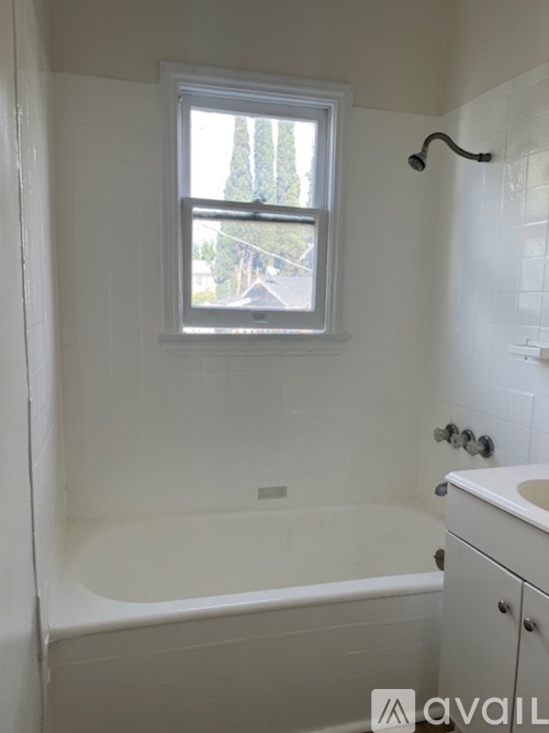 A bathroom with a tub, sink and window.