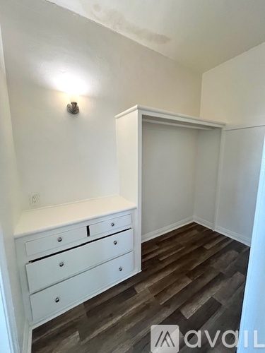 A white drawer unit sits on a wooden floor in a room.