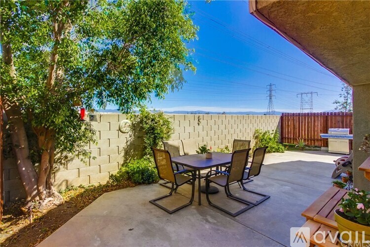 A patio with a table and chairs is surrounded by a wall and trees.