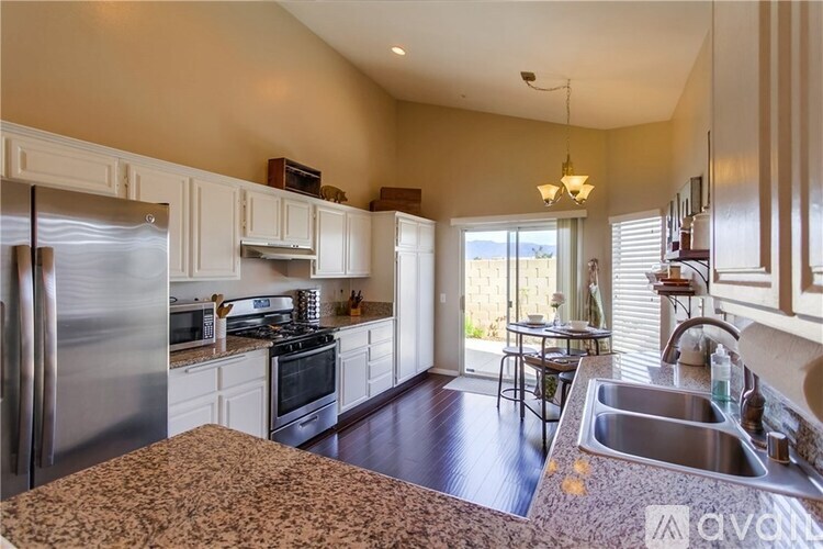 A kitchen with a refrigerator, sink, and stove.