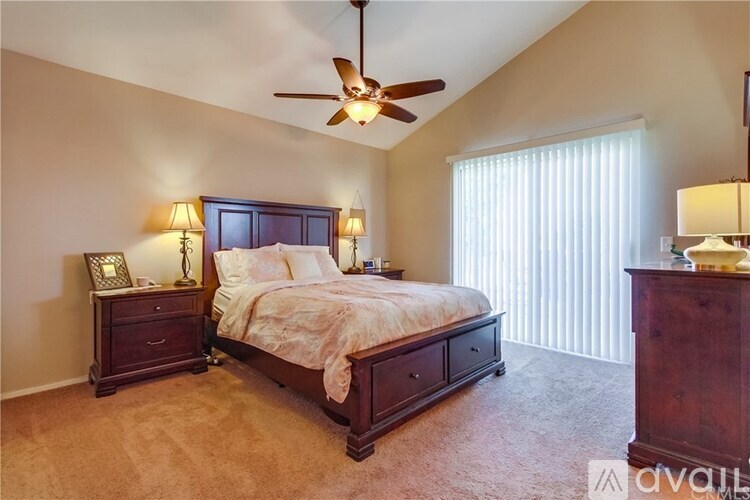 A bedroom with a bed, nightstand, and a ceiling fan.