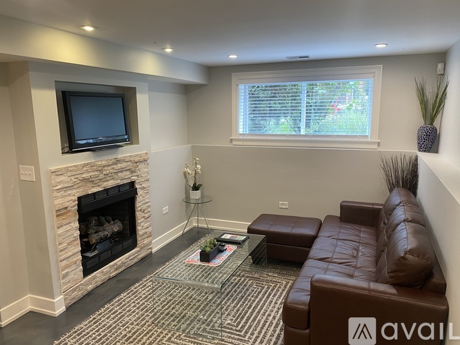 A living room with a fireplace and a brown leather couch.