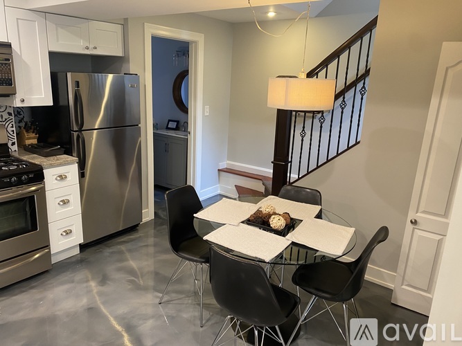 A kitchen with a table and chairs in front of a staircase.