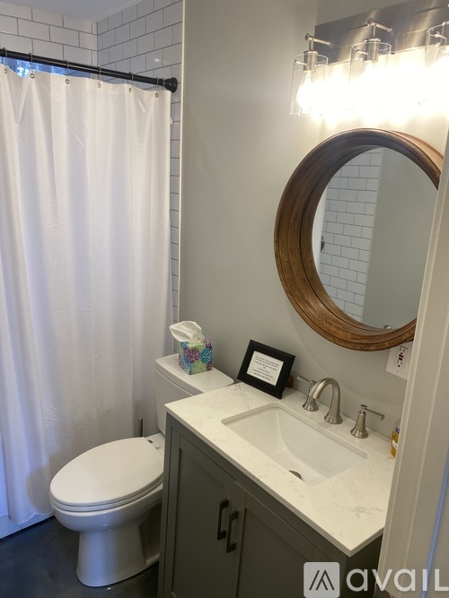 A bathroom with a white toilet, a sink with a mirror above it and a shower curtain.