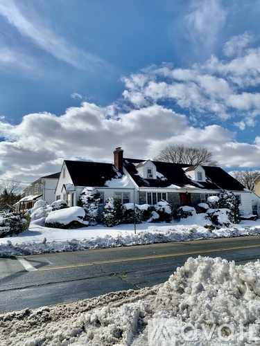 A house with a snow-covered ground and a cloudy sky.