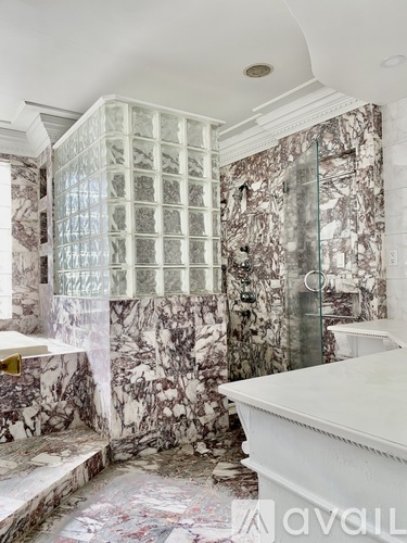 A bathroom with marble walls and a glass block shower.