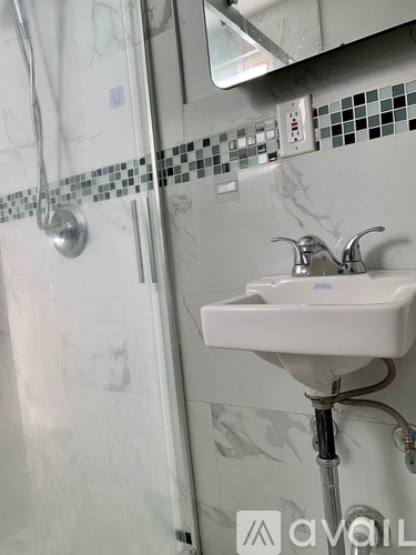A white sink in a bathroom with a mirror above it.