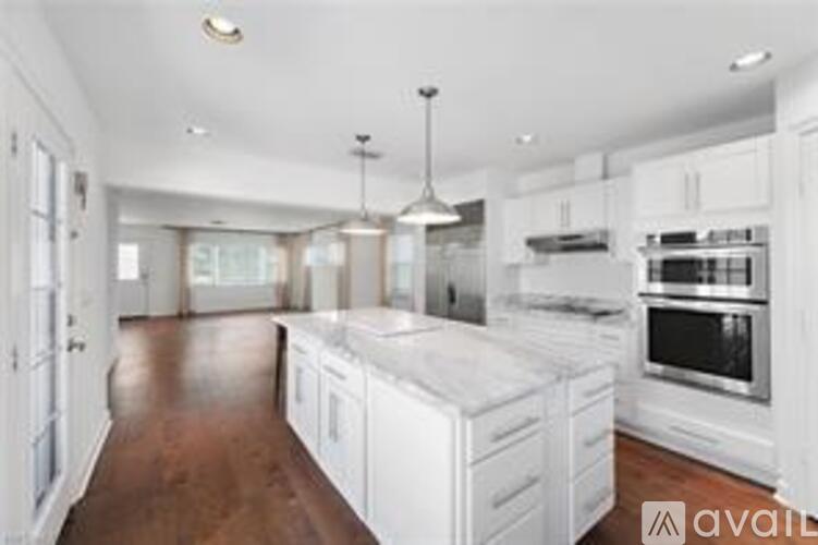 A kitchen with white cabinets and a wooden floor.