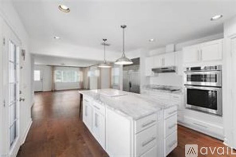 A kitchen with white cabinets and a wooden floor.