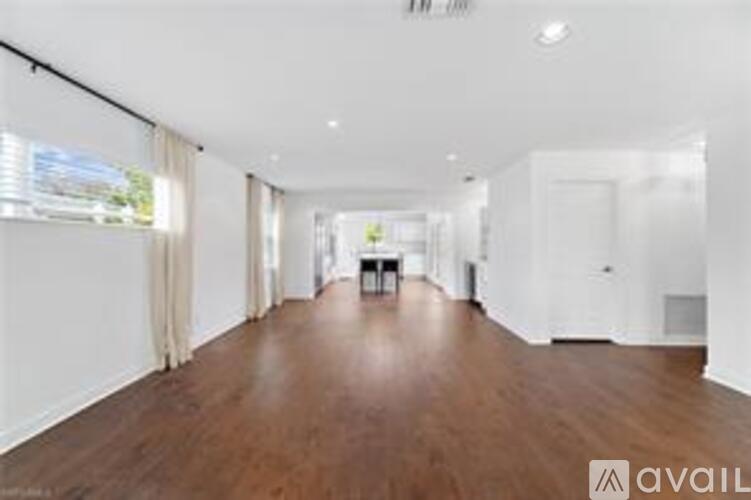 A spacious room with wooden floors and white walls.