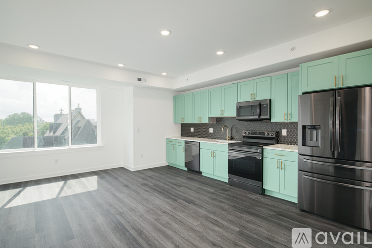 A modern kitchen with stainless steel appliances and teal cabinets.