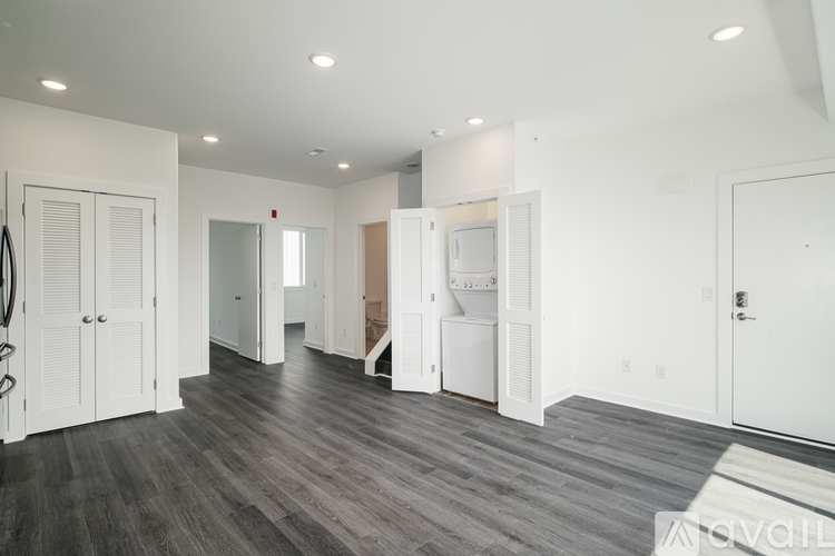 A spacious room with white walls and wooden flooring.