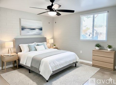 A bedroom with a large bed, a ceiling fan, and a window with blinds.