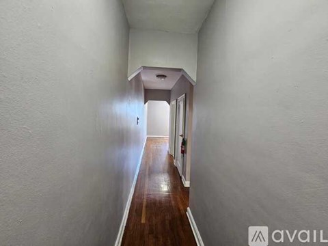 A long hallway with white walls and wood flooring.