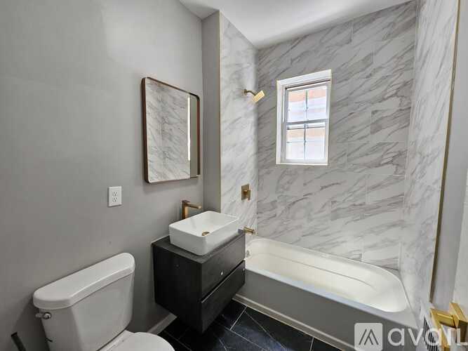 A bathroom with a marble wall and a white toilet.