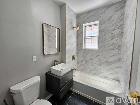 A bathroom with a marble wall and a white toilet.