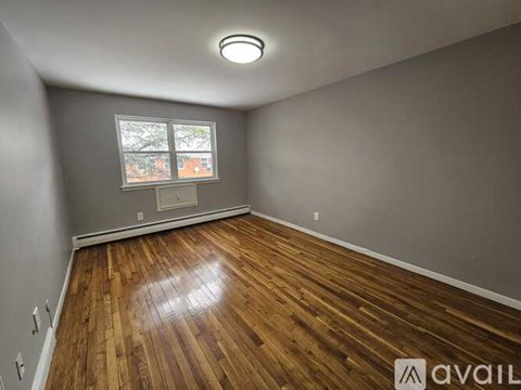 A room with wooden flooring and a window showing a view of buildings outside.
